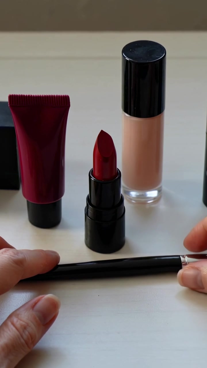 Vertical video: Entering right hand placing red lipstick sliding brush, tube, base on sill to show