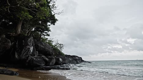 Monochrome-shot-Of-Waves-Crash-On-sandy-seashore-and-rocks-In-Dam-Trau-Beach,-Vietnam