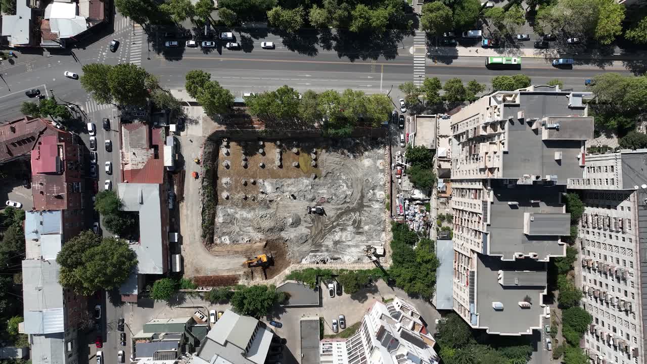 una toma aérea de un lote excavado rodeado de edificios de la ciudad, listo para la construcción de un nuevo proyecto