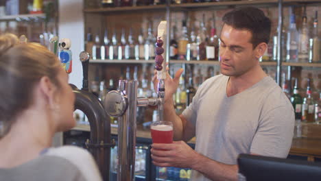 female customer in bar makes socially distanced contactless payment for drinks in health pandemic