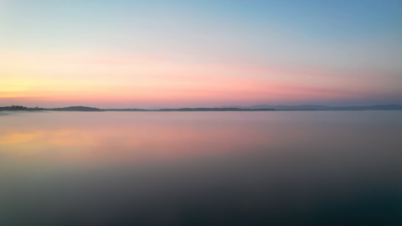 Pastel Hues of Sunrise Reflected on a Misty Lake