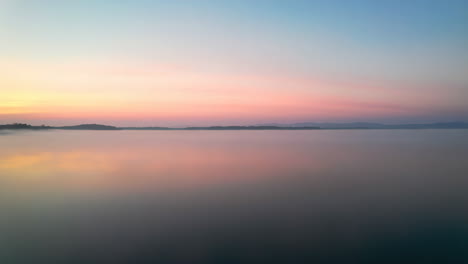pastel hues of sunrise reflected on a misty lake
