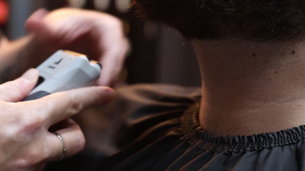 Shot of barber trimming beard of male client with hair clippers while working in Barber shop