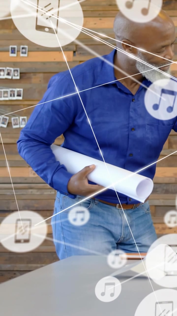 Video verticale: Un designer esamina i progetti, si avvicina al tavolo e genera un overlay con icone musicali del telefono.