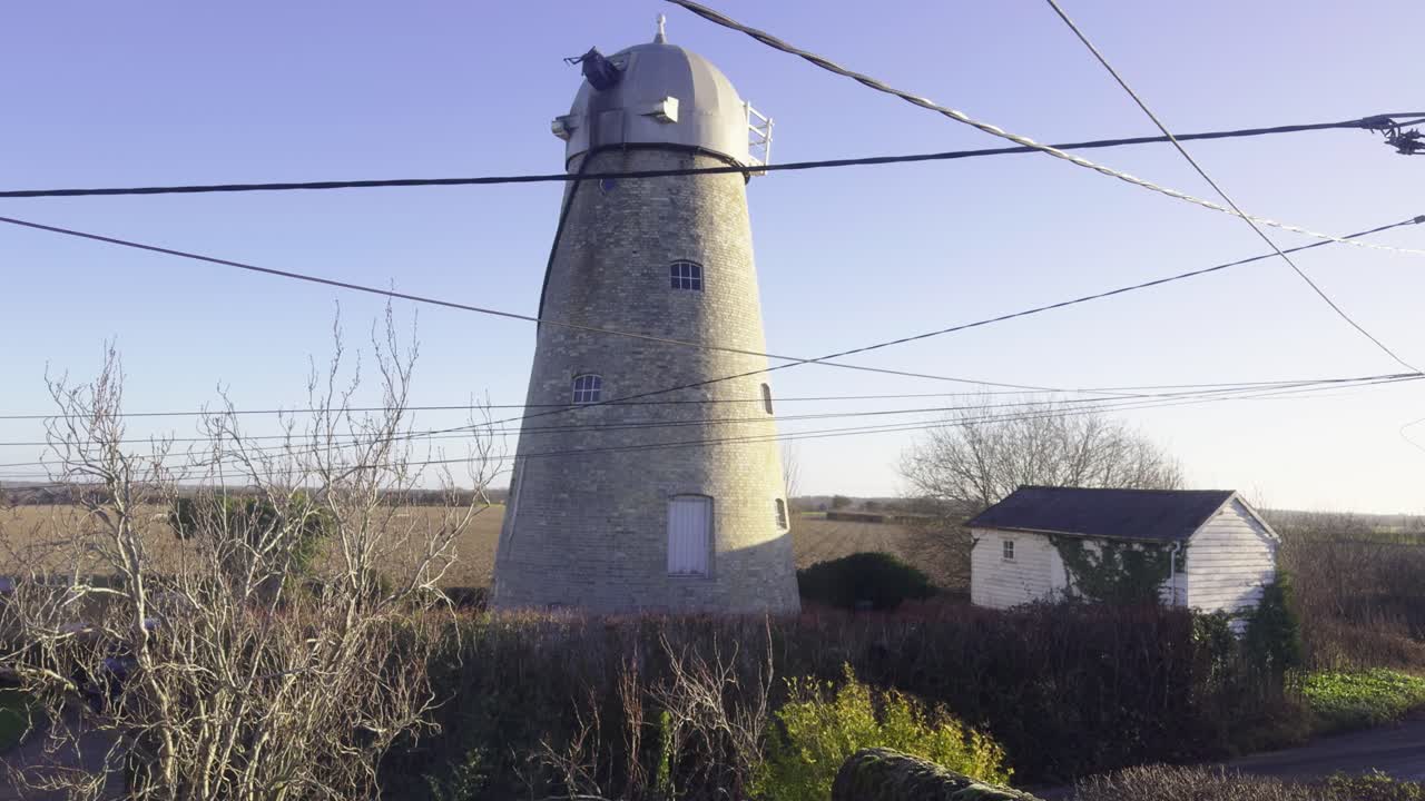 Un vecchio mulino a vento vicino a un campo nella campagna del Regno Unito in una giornata ventosa