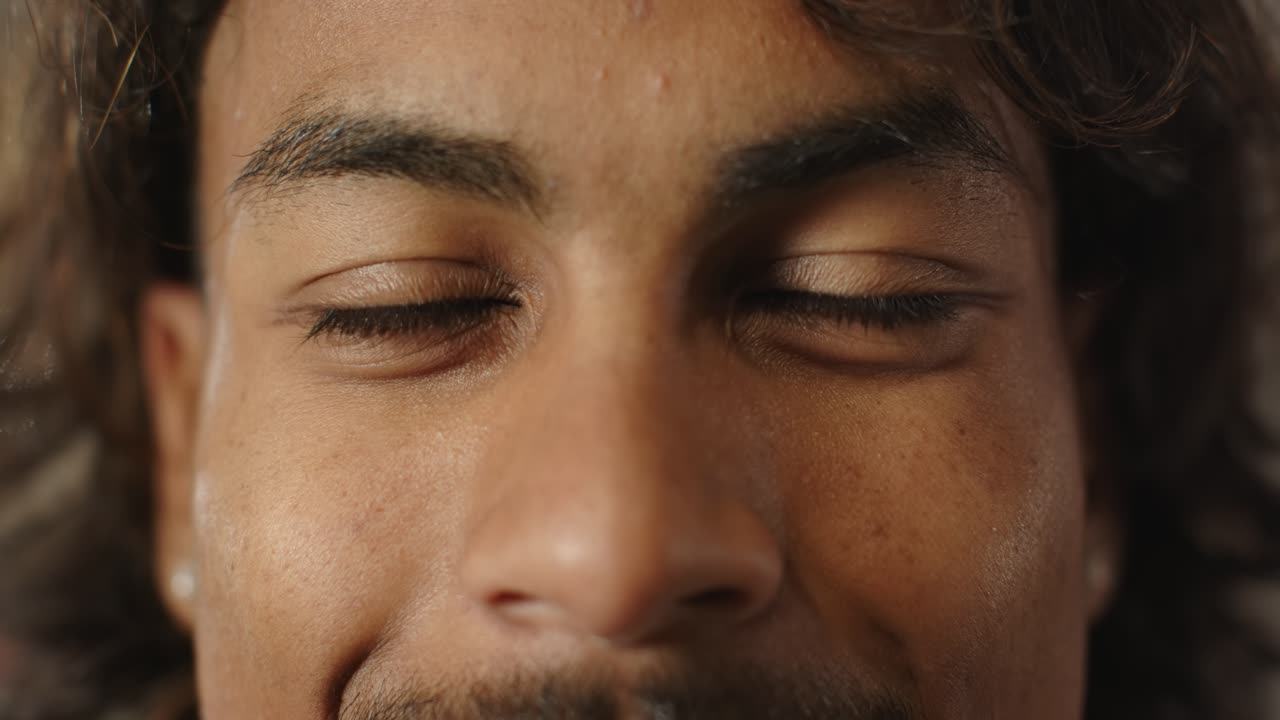 African American man blinking then smiling into broad grin in close-up with ear stud visible