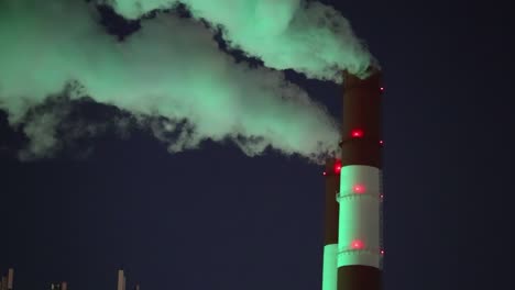 green smoke from chimney of night industrial cityscape with carbon emissions from factory