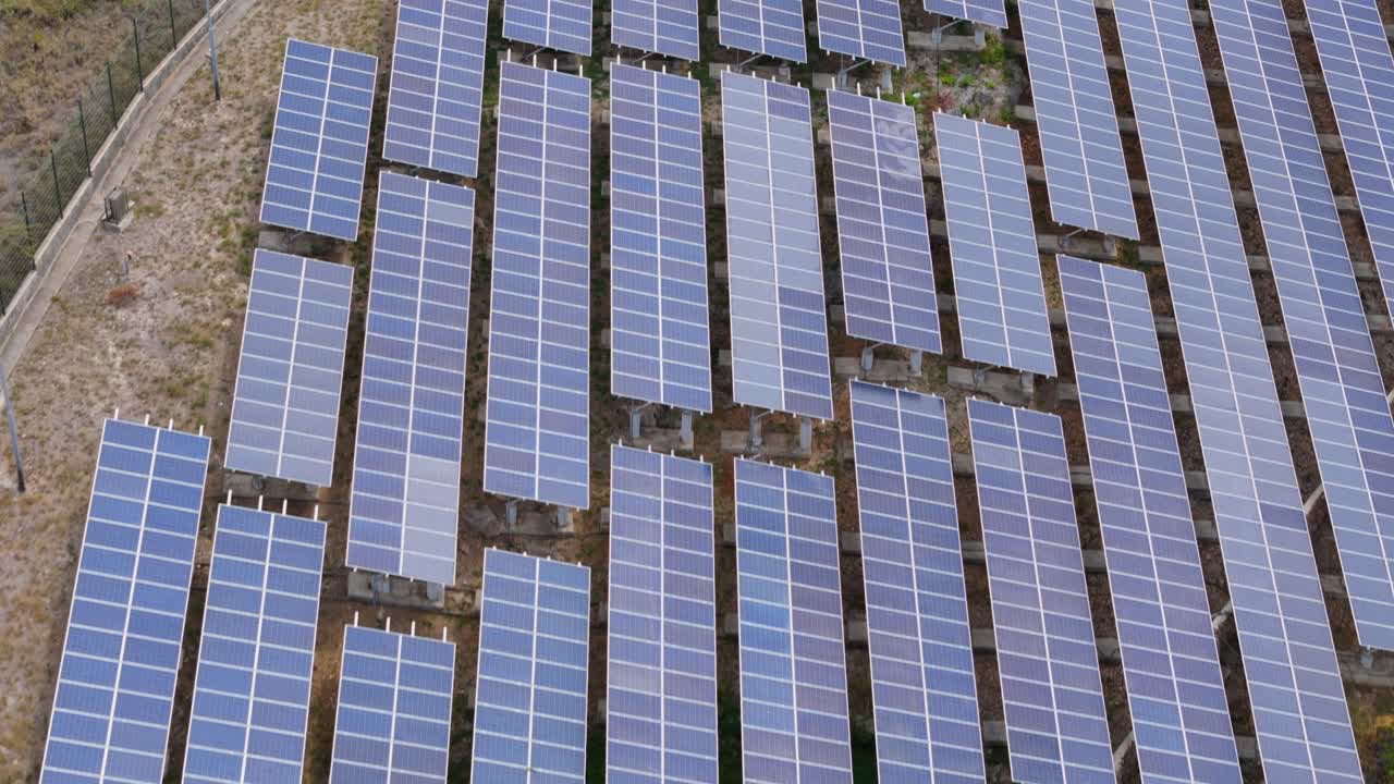 Top-down view of solar panel arrays on hillside in a tropical Caribbean island environment