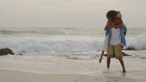 african american man giving piggyback ride to woman on the beach 4k