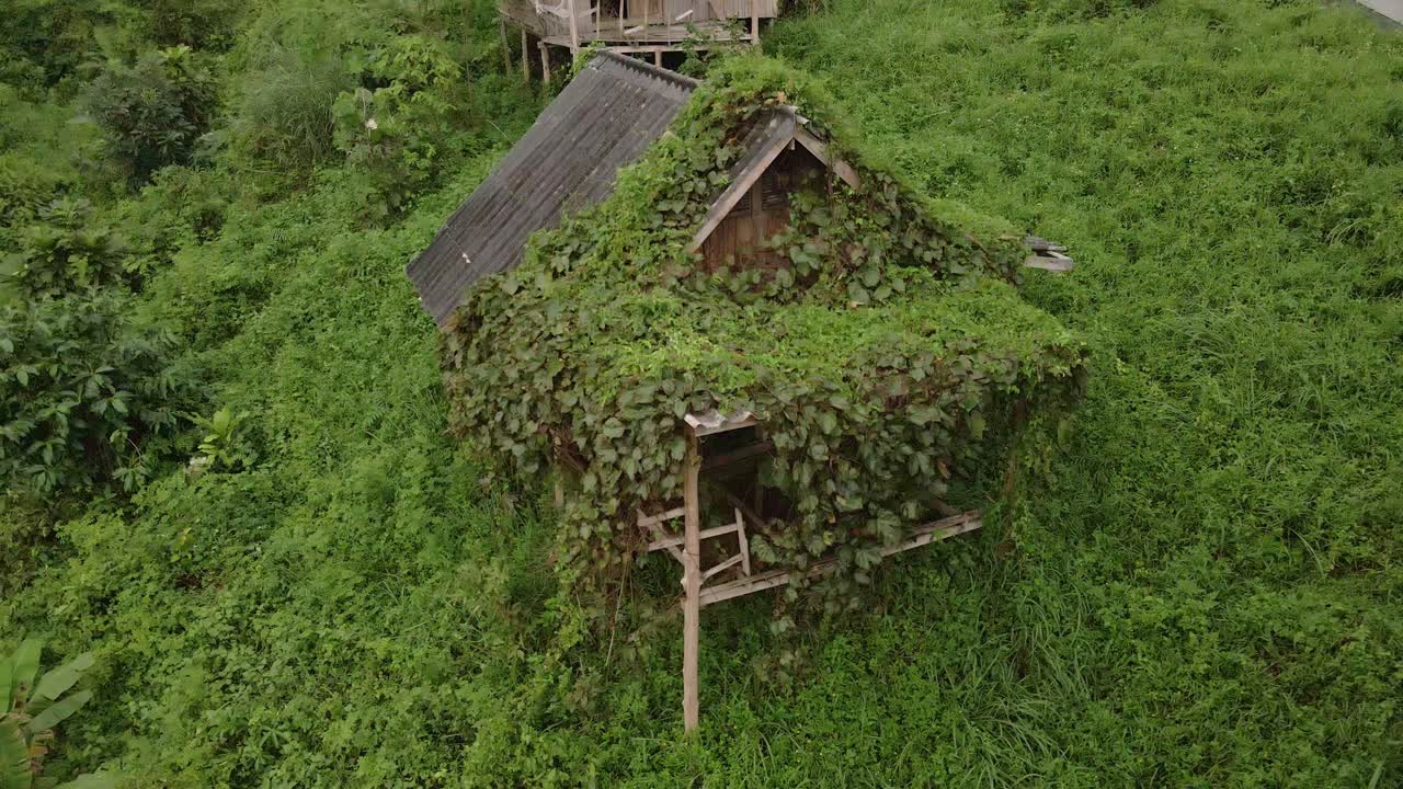 drone inclinado hacia arriba, vista aérea de pájaros de un bungalow tailandés de madera de estilo antiguo que está cubierto de follaje que ahora está abandonado y sin usar debido a los efectos de la pandemia en los viajes y el turismo