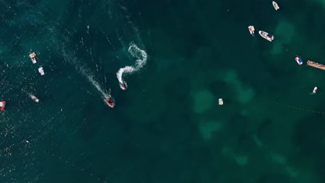 boats and jet skis create white trails on the blue-green waters of ksamil, albania from an aerial view