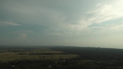 Statische-Zeitrafferaufnahme-Einer-Weiten-Landschaft-Mit-Bäumen-Und-Großen-Feldern,-Während-Wolken-Am-Horizont-Vorbeiziehen