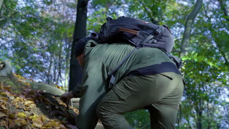 man hiking on rocky mountains during sunny day in forest