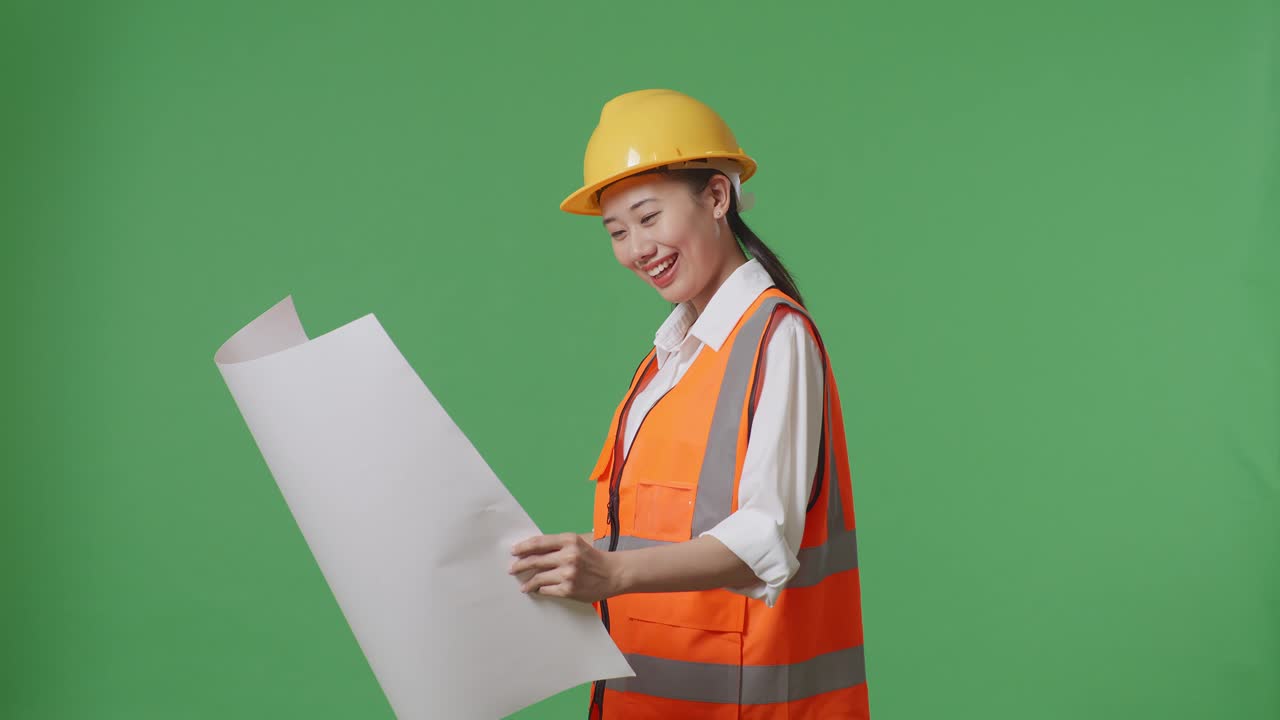 녹색 스크린 배경 스튜디오에 서 있는 동안 안전 헬을 착용 한 아시아 여성 엔지니어의 측면 시각