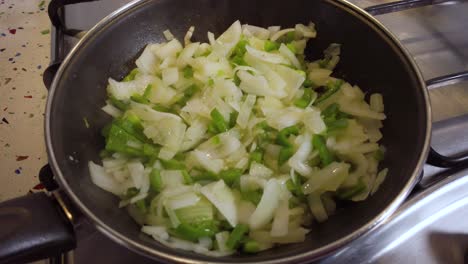 detalle de primer plano del vapor lento que se eleva de la cebolla y el pimiento verde en la sartén