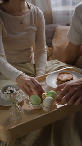 una pareja disfrutando del desayuno de pascua en la cama.