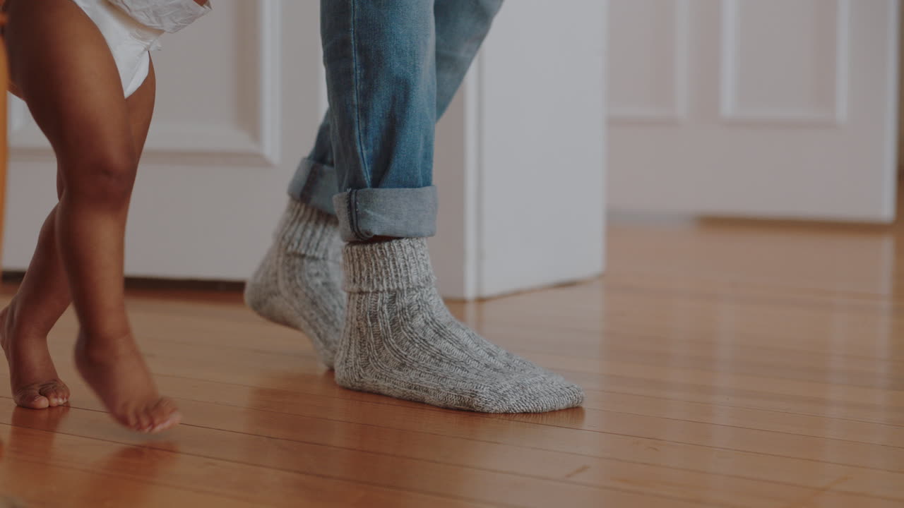 cerca de los pies bebé aprendiendo a caminar niño pequeño dando sus primeros pasos con el padre ayudando al bebé enseñando al niño en casa