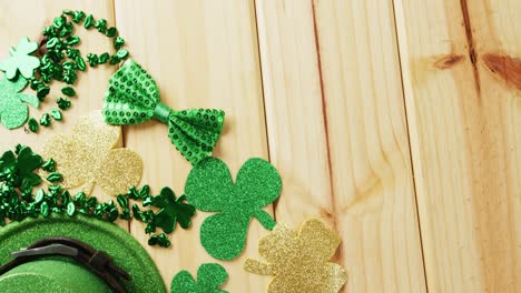 video of st patrick's green hat, shamrock and bow tie on wooden background