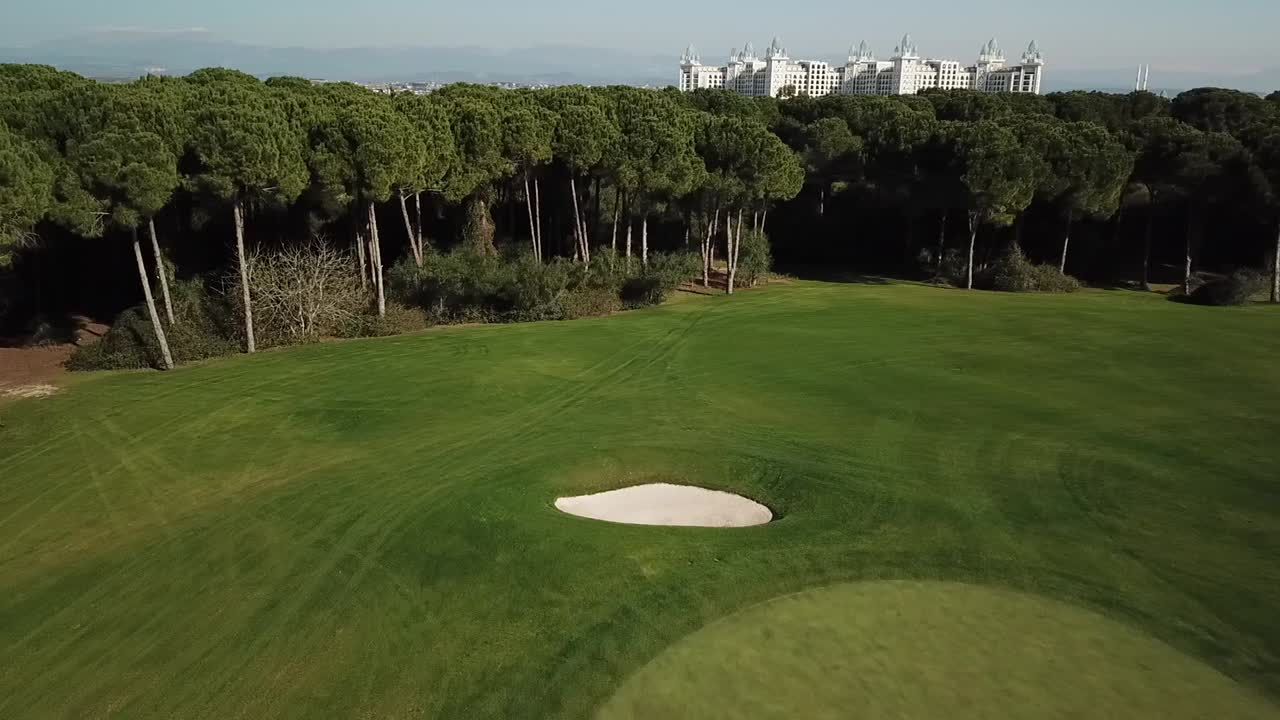 Palo della bandiera con bandiera su un lussuoso campo da golf, ripreso in circolo