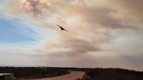 fire fighting airplane flying over fairview wildfire in californiamassive flames and smoke clouds cover a hill ridge in hemet, california