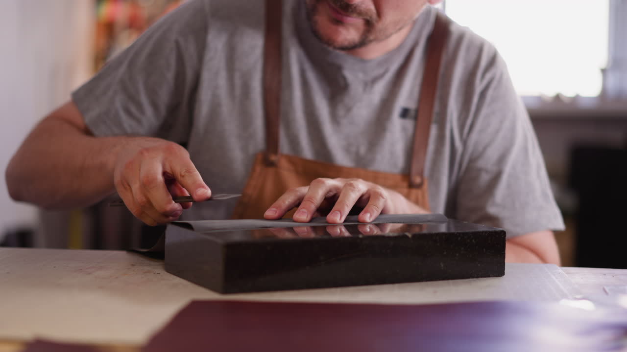 Craftsman sharpens cutter with sandpaper at table in shop