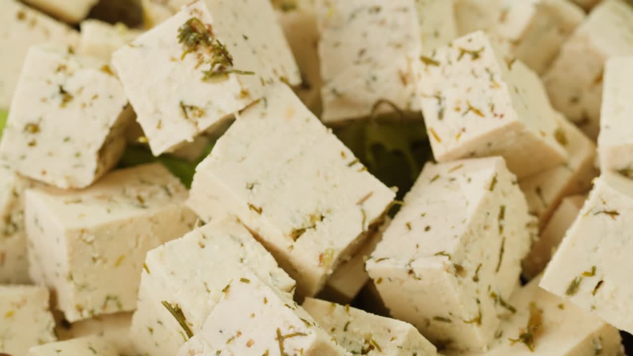 Fried tofu with sesame seeds and spices on cast iron pan, cooking japanese salad. Healthy ingredient for cooking vegan vegetarian diet food. Roasted tofu over black background.