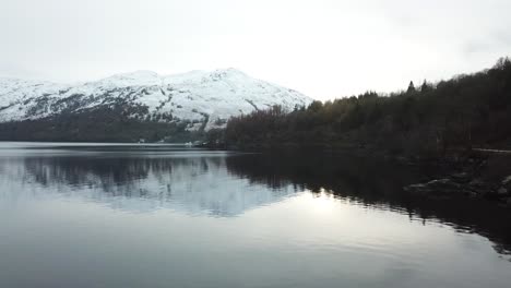 White-snow-covered-the-tops-of-the-mountain-in-the-background-with-trees-in-autumn-colors-next-to-loch-Lomond-in-Scotland