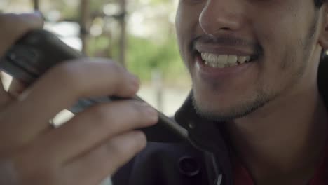 Close-up-view-of-happy-bearded-man-talking-by-cell-phone