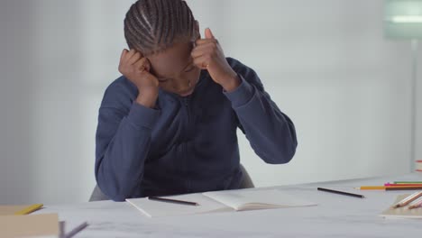 Boy-On-ASD-Spectrum-At-Table-At-Home-Struggling-With-Concentrating-On-Writing-In-School-Book-3