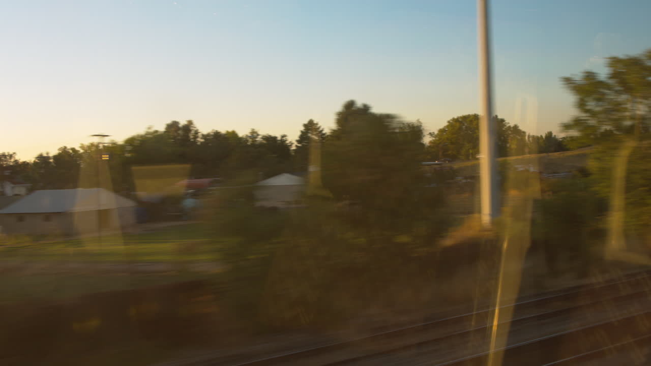 A view from a commuter train's window passing a small town and houses in an urban neighborhood.
