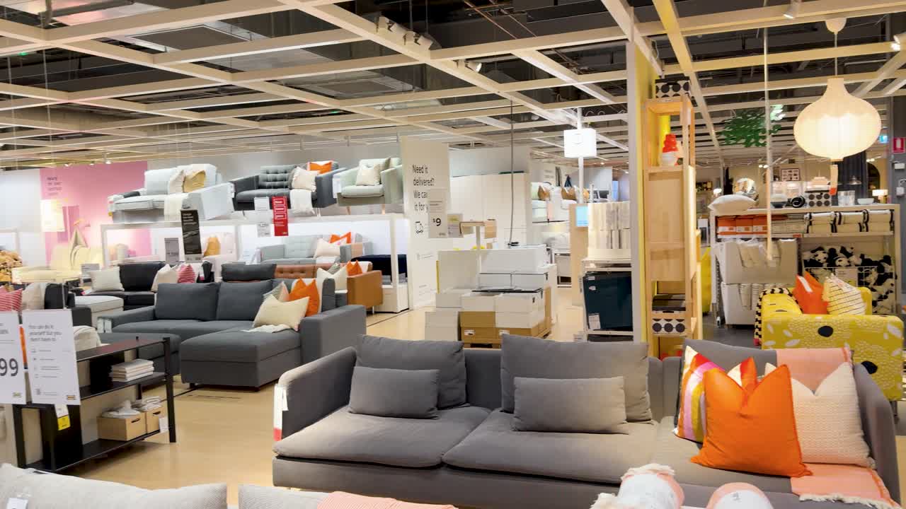 Camera glides past sofas and decor in brightly lit, contemporary furniture showroom interior