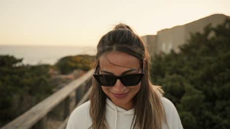 mujer alegre feliz caminando con gafas de sol, sonriendo felizmente mientras hace senderismo