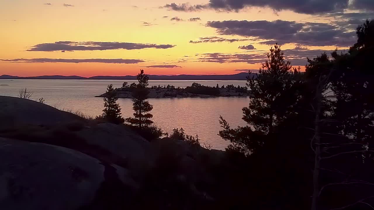Fly Past Inukshuk on Rocky Pine Tree Island just after Sunset, Drone Aerial Wide Dolly In