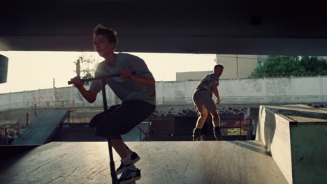 teenage athletes performing stunt together at city bright sun skate park.