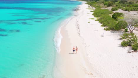 Man-and-woman-walk-along-white-beach-near-Eco-Del-Mar,-Pedernales