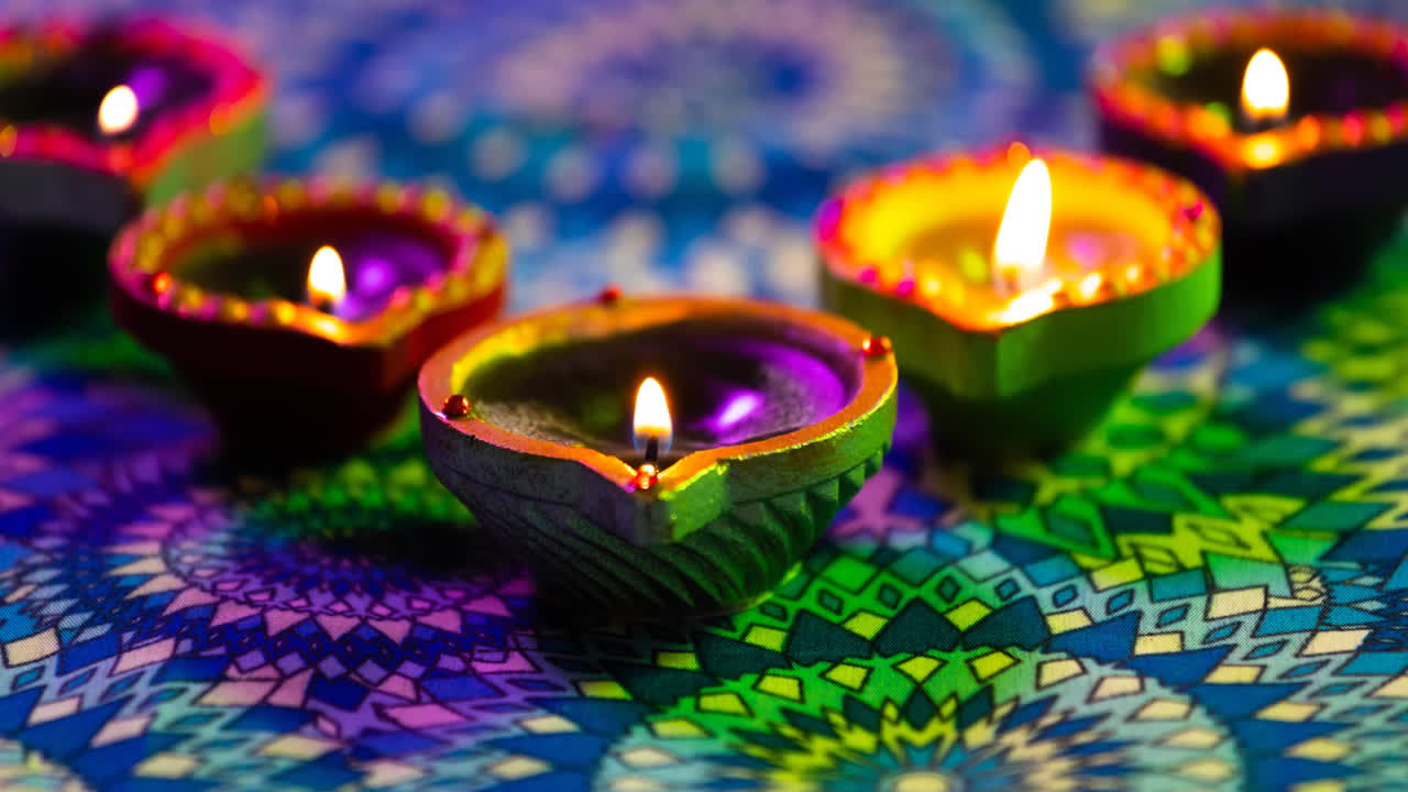 video de velas de diwali encendidas brillantes en una superficie con patrón de púrpura a verde