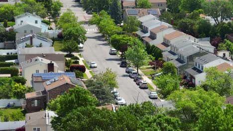Aerial-panorama-view-showing-parking-cars-in-american-residential-area-with-green-trees-at-sunny-day---zoom-lens-drone-shot