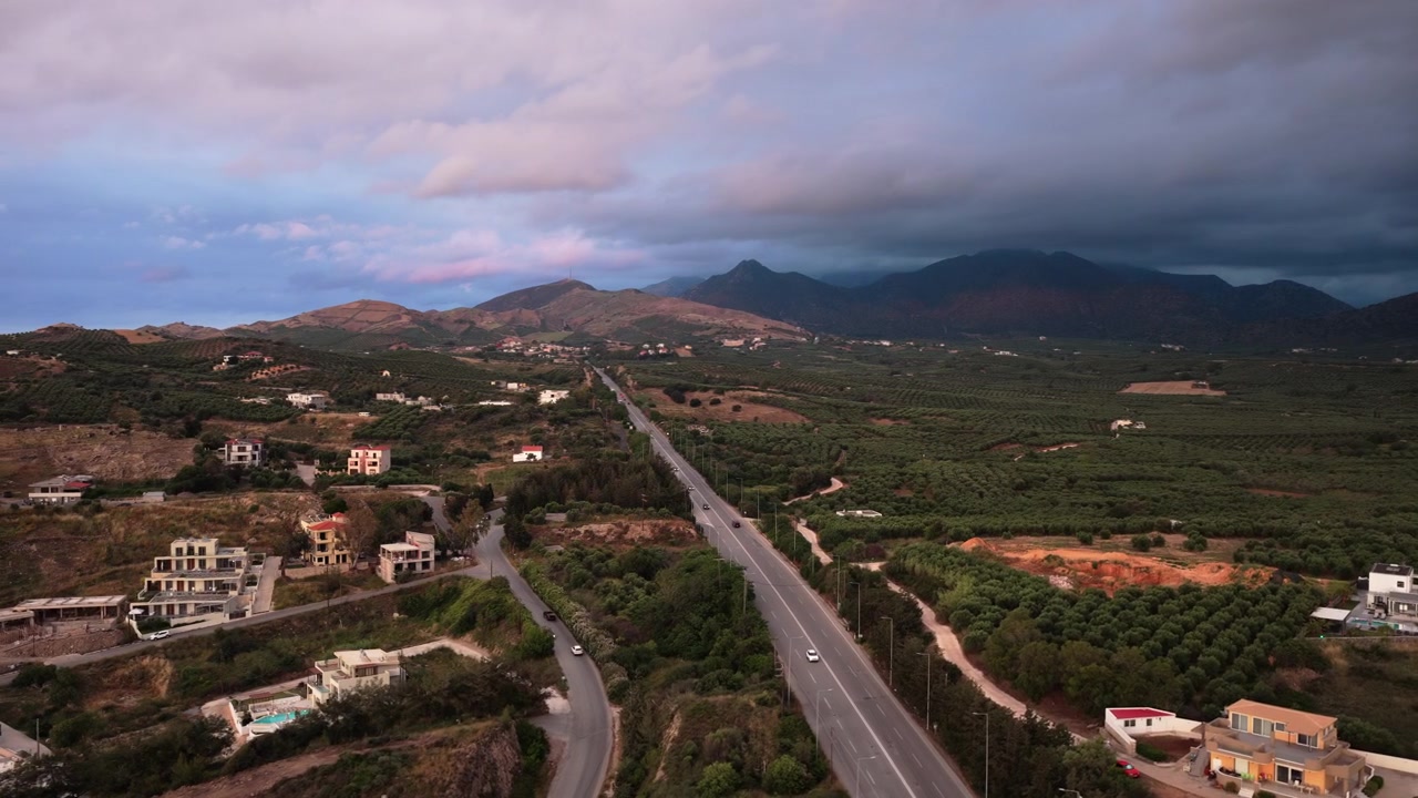 Vista aerea con drone di una pianura costiera di uliveti e frutteti che si estende verso le montagne, Creta, Grecia