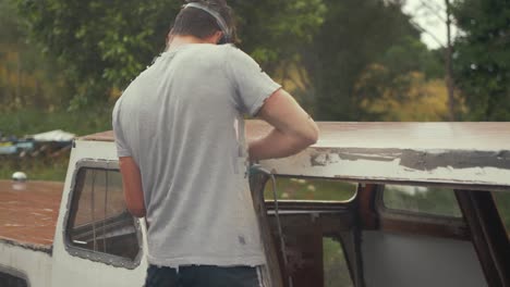 Young-carpenter-belt-sanding-roof-of-wooden-boat