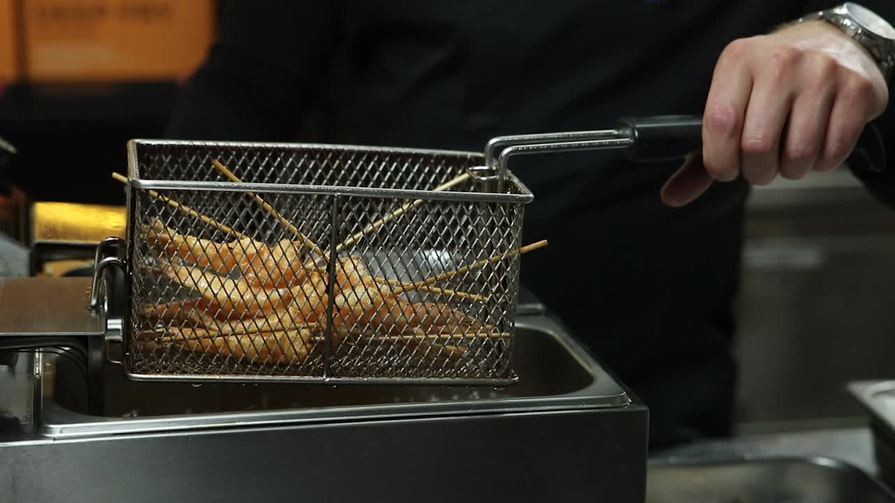 셰프가 깊은 프라이어에서 새우를 고 있습니다.