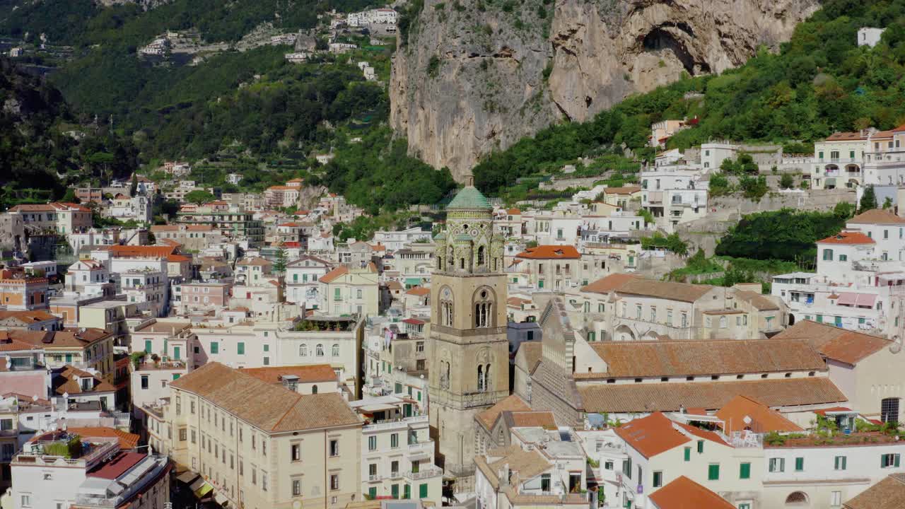 Volando verso il campanile della cattedrale nella città di Amalfi. Vista aerea con drone dell'architettura storica italiana sulla Costiera Amalfitana in una soleggiata giornata estiva.
