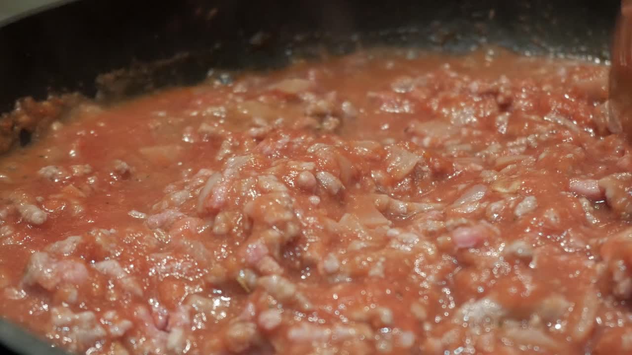 Simmering Bolognese sauce with meat in a pan, comforting home cooking