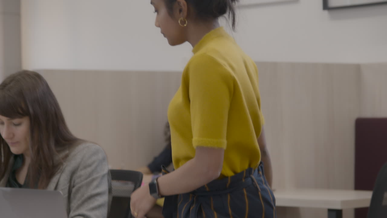 Woman Handing Post It Note To Colleague