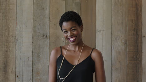 portrait of young independent african american woman smiling dancing lively looking at camera cheerful happy beautiful trendy black female wooden background lobby