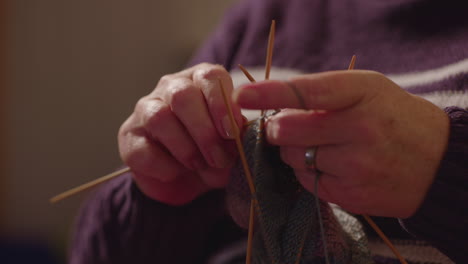 Elderly-woman-sitting-and-knitting,-static-close-up,-slow-motion-cinematic
