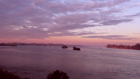 As-the-sun-dips-below-the-horizon,-casting-a-warm-glow-over-the-serene-lake,-clouds-paint-the-sky,-creating-a-cinematic-scene-with-boats-peacefully-adrift-in-the-midst