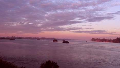 cuando el sol se sumerge bajo el horizonte, proyectando un brillo cálido sobre el sereno lago, las nubes pintan el cielo, creando una escena cinematográfica con barcos a la deriva pacíficamente en el medio