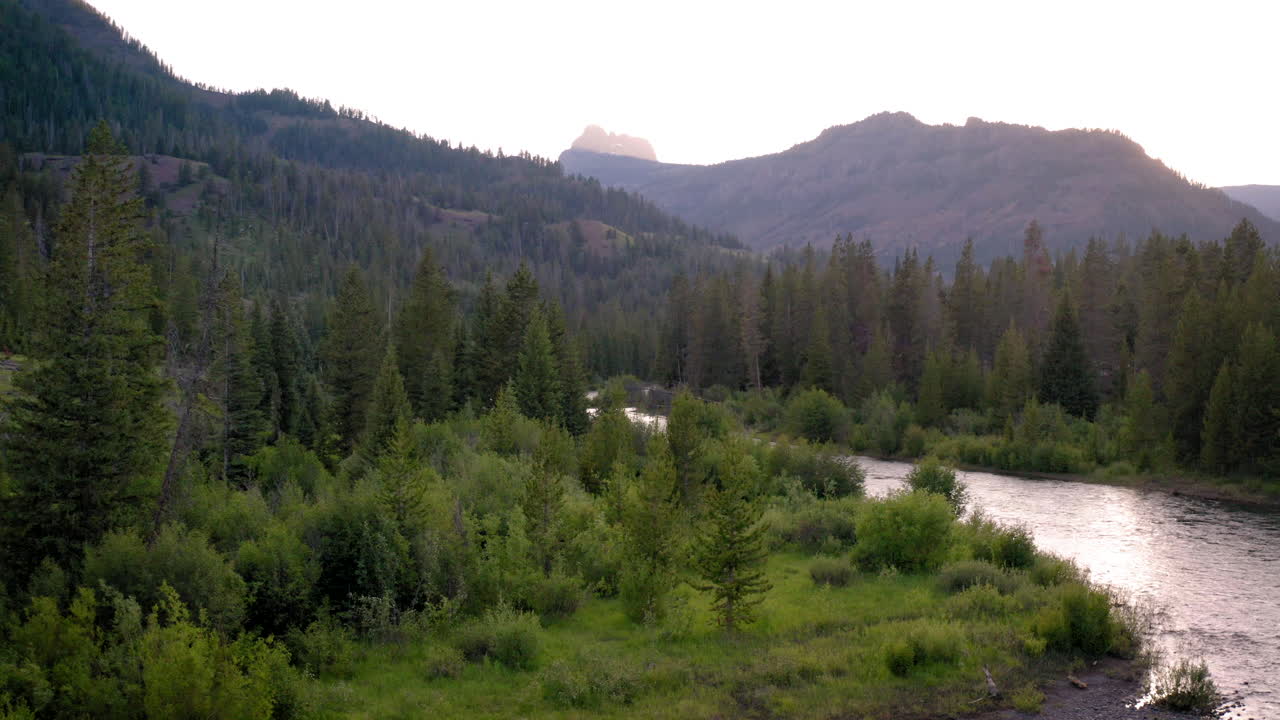 River flowing through a forested mountain valley at dawn or dusk
