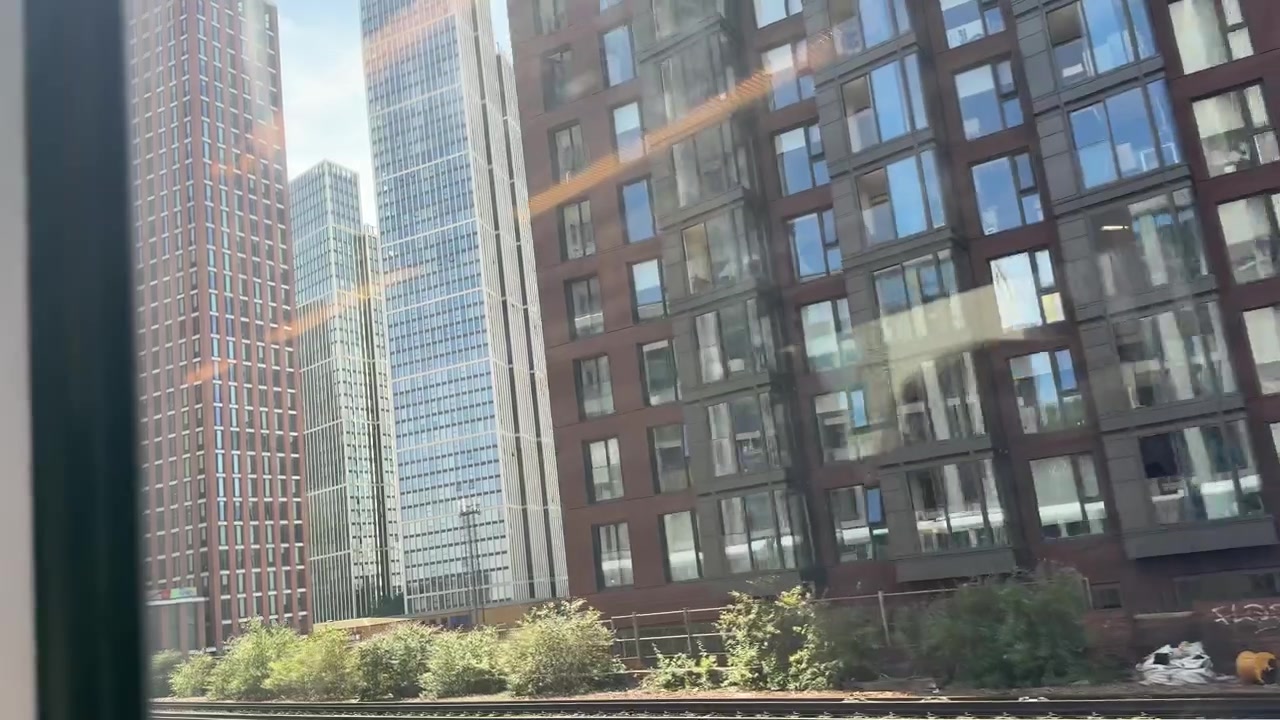 Um trem passa por Vauxhall, Londres, Inglaterra, revelando arranha-céus modernos e uma estação de trem movimentada em um dia ensolarado