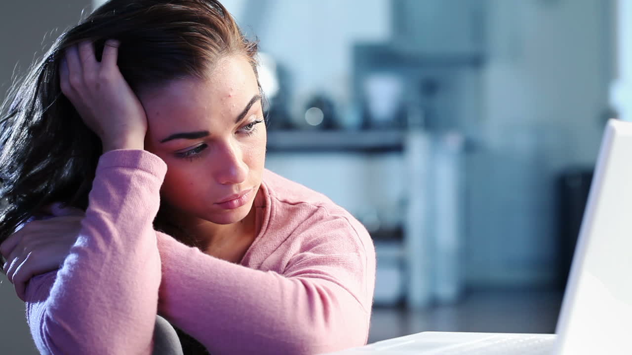 Ragazza adolescente triste e depressa che usa il portatile.